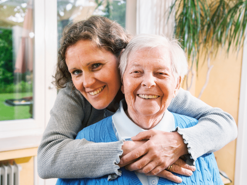 A woman hugging her mother in Holly Hall senior care community.