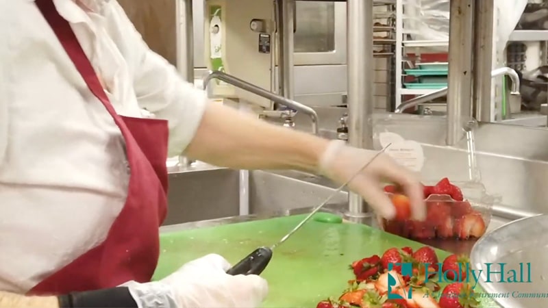 A chef preparing strawberry fruit salad for Holly Hall residents.