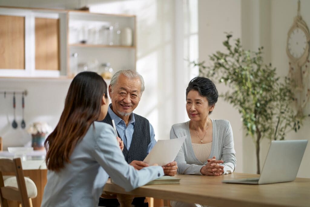 Senior couple reviewing financial documents with adult daughter at home, planning for Christian senior care